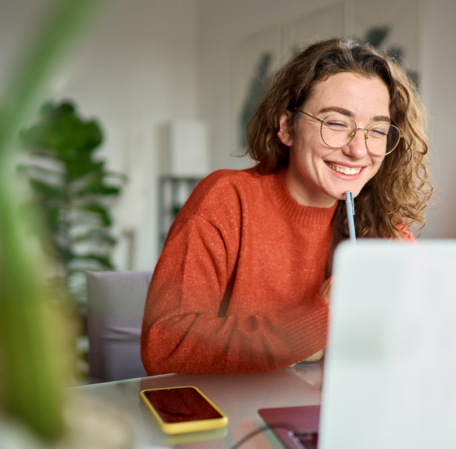 Happy student in orange top studying on laptop